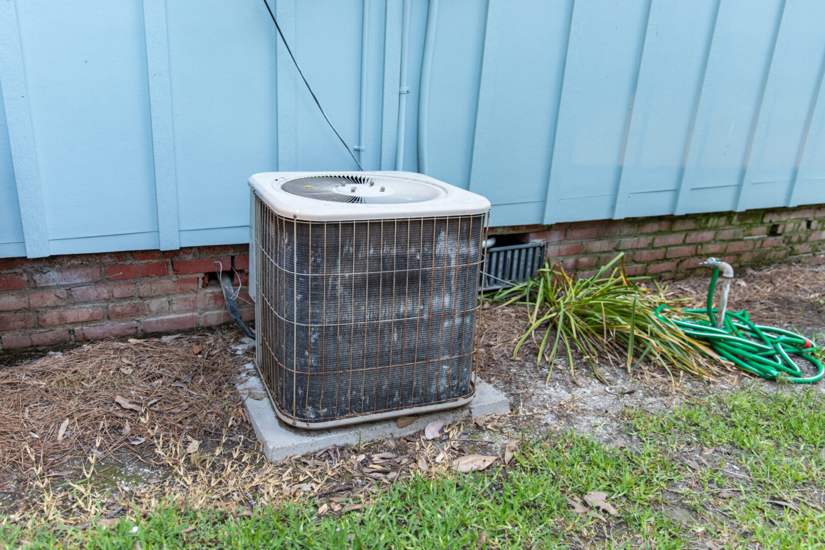 A dirty air conditioner sitting outside of the house.