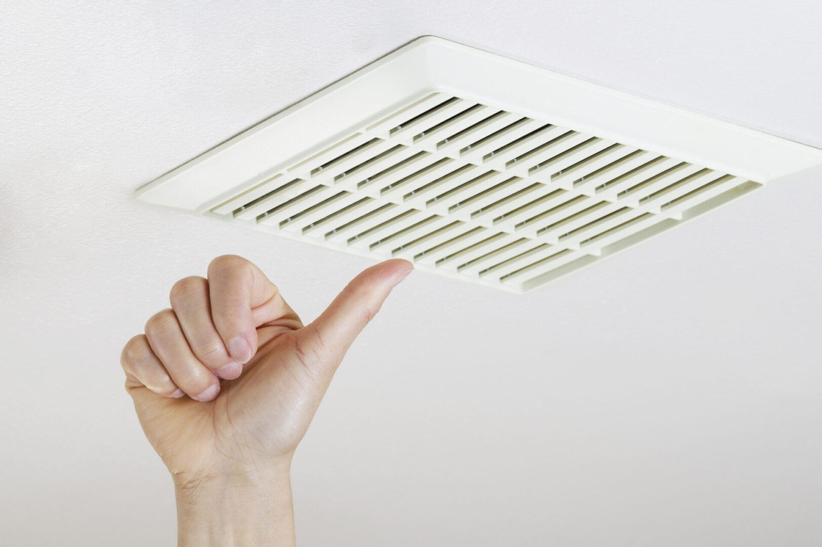 A hand is pointing to the vent in the ceiling.