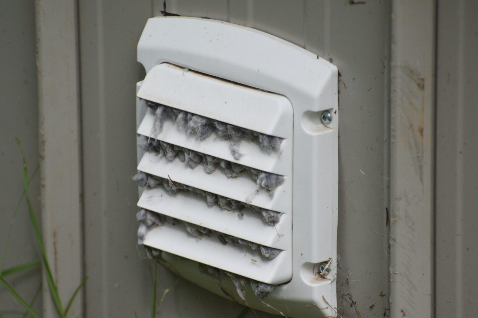 A white vent mounted to the side of a building.